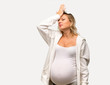 Pregnant blonde woman with white sweatshirt intending to realizes the solution on isolated grey background