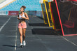 © Andrii - Runner listening to smart phone music app on running tracks. woman athlete with earphones and smartphone ready to do run cardio workout at track and field stadium. Jogging motivation