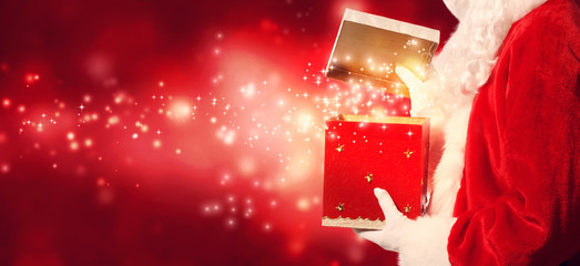 Santa opening a gift box on a shiny light background