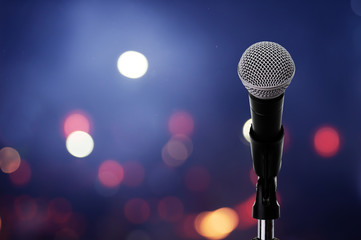 microphone on stage ..close up of microphone setting on stand with colorful light bokeh background i