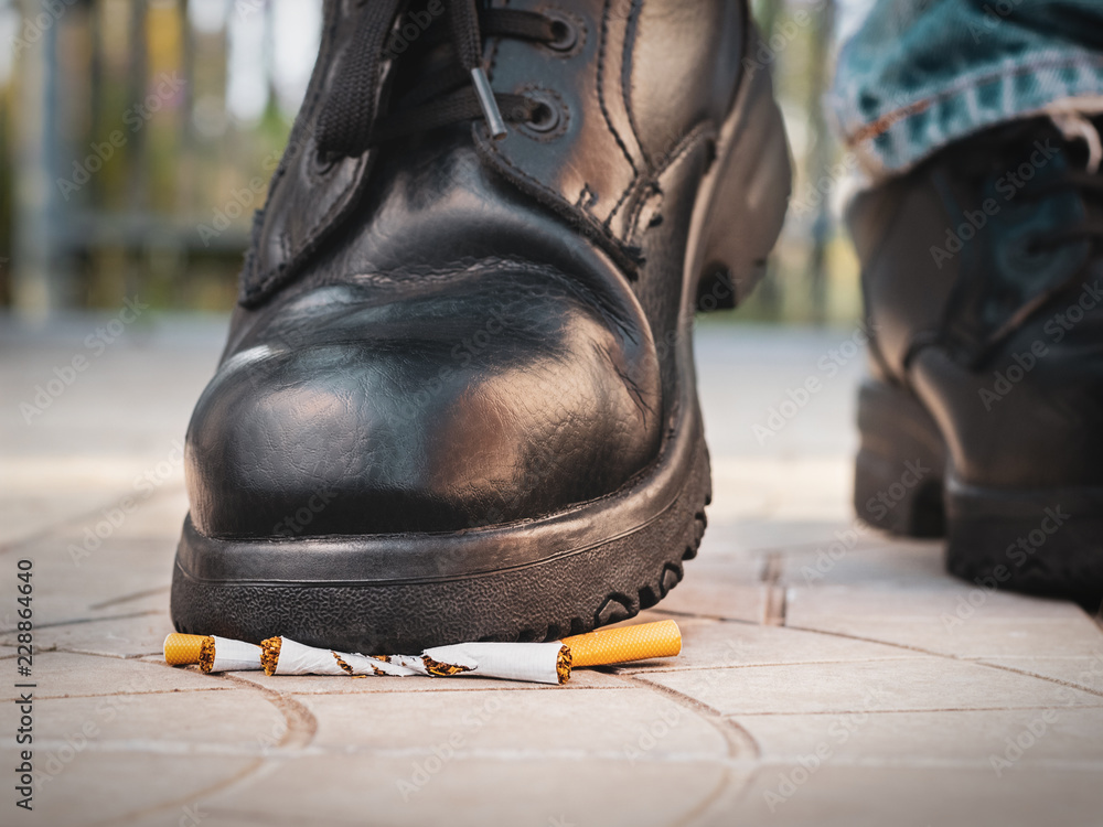 cigarette shoe Male foot in black shoes crushing cigarettes Stock Photo