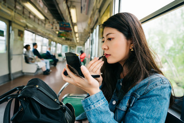 an elegant lady doing makeup on the subway