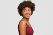 © WHstudio Leushin N - Sideways shot of pleased relaxed woman with healthy dark skin, looks positively aside, has slim body, notices something pleasant back, poses in studio against white background. People and emotions