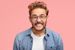 © WHstudio Leushin N - Photo of pleased curly Caucasian man smiles joyfully at camera, clenches teeth, dressed in fashionable blue shirt, being in good mood after date with girlfriend, poses against pink background