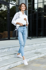 Wall Mural - Cheerful young woman walking outdoors at the street