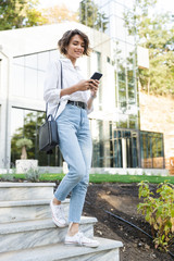 Canvas Print - Cheerful young woman in earphones walking downstairs