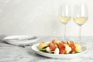 Melon, mozzarella and prosciutto skewers served on marble table. Space for text