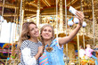 © New Africa - Attractive women taking selfie in amusement park