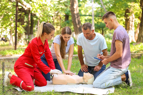 Fotografía Group of people having first aid class with mannequin outdoors