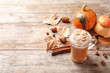 Glass cup with tasty pumpkin spice latte and space for text on wooden table