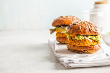 Vegan sweet potato (or pumpkin) burgers on white background. Vegetable burgers, avocado, vegetables and buns, copy space.