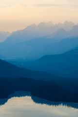 The orange glow of sunset over Peyto Lake in Banff National Park with distant moody mountains