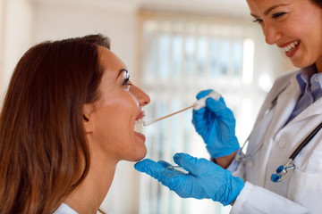 Young woman doctor takes a swab from the throat