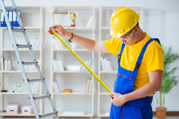 Young contractor doing repair works at office 