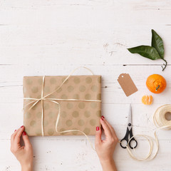 Wall Mural - Closeup of a girl's hands wrapping a gift for Christmas, birthday or any other holiday. Gift preparation for the celebration. Festive season