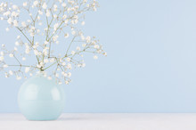 Spring Branch With Small White Flowers In Blue Sphere Vase In Soft Light Blue Modern Interior, On A White Table.
