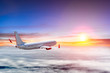Airplane flying above clouds at colorful sunset. Lens flare effect.