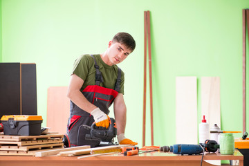 Wall Mural - Young man carpenter working in workshop 