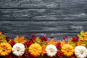 Wall Mural - top view of autumn maple leaves with pumpkin and red berries on old wooden backgound. thanksgiving d