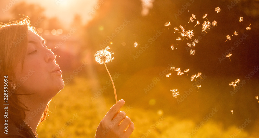 Junges Mädchen bläst Samen einer Pusteblume, Sonnenuntergang im Herbst mit Textfreiraum - obrazy, fototapety, plakaty 