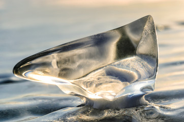 Ice floe at frozen lake surface with reflection. Deep cracks in the ice and ice reflection