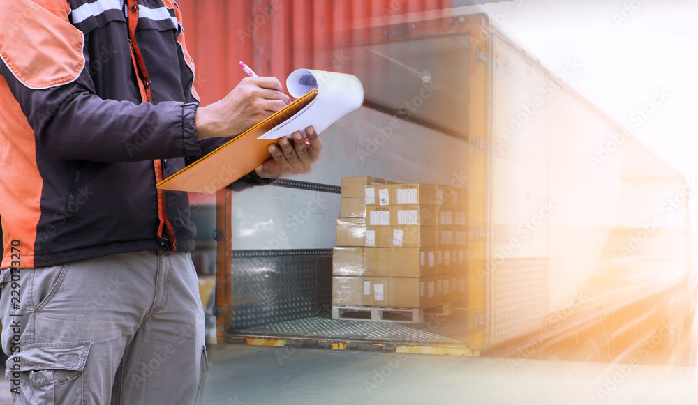 Warehouse worker holding clipboard with control loading shipment goods into container truck. Road freight cargo shipping logistics and transportation. - obrazy, fototapety, plakaty 