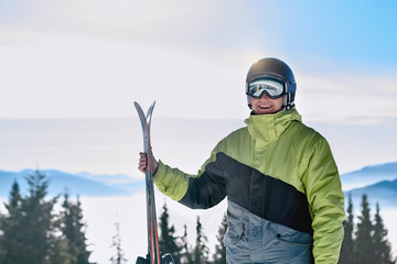 Wall Mural - Portrait of a skier in the ski resort on the background of mountains and blue sky, Bukovel.  Ski goggles of a man wearing ski glasses. Winter Sports