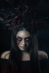 Terrible horror Halloween Vampire Woman portrait. Beauty Vampire Witch lady with blood on mouth posing in deep forest. Fashion Art design. holds a candle in his hands and reads curses