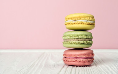 Stacked French macaroons on wooden table and pink background