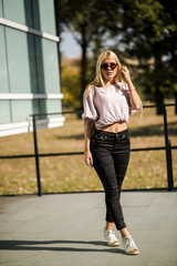 Photographing a girl during autumn near a high-tech glass building with a blurred background of the park