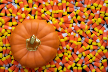Orange Ceramic Pumpkin With A Gold Stem Sitting On A Background Of Halloween Candy Corn 
