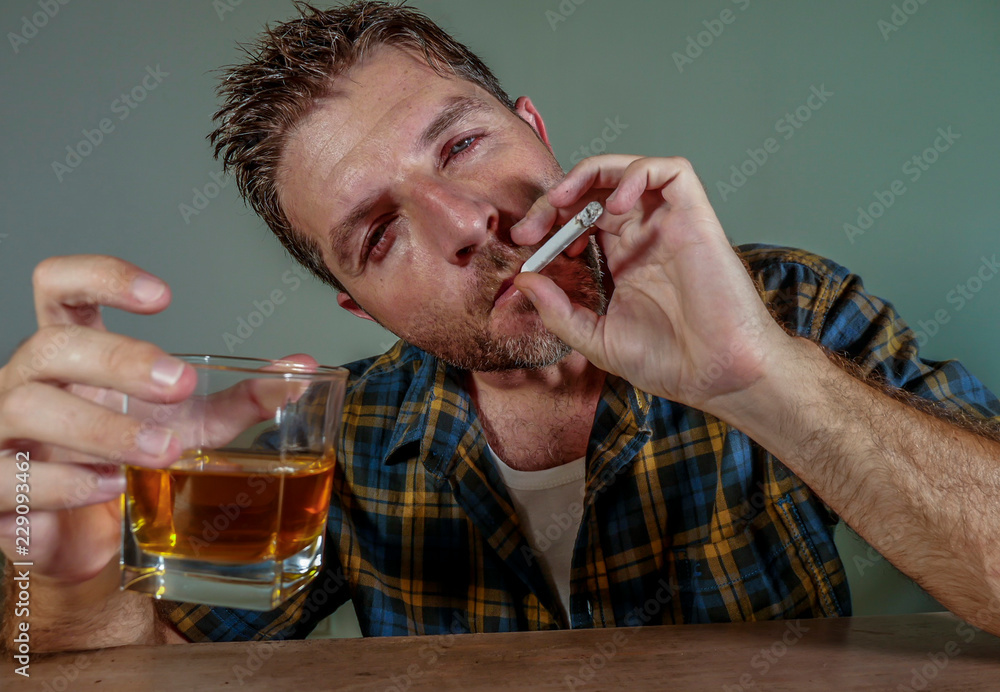 Photo Stock young messy and wasted addict man smoking cigarette having  alcoholic drink looking at whiskey glass suffering alcoholism and tobacco  addiction in unhealthy habit