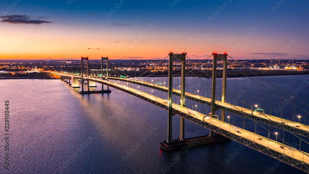 Aerial view of Delaware Memorial Bridge at dusk. The Delaware Memorial Bridge is a set of twin suspension bridges crossing the Delaware River between the states of Delaware and New Jersey - obrazy, fototapety, plakaty 