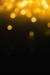 Wall Mural - golden christmas bokeh lights on dark background. abstract yellow glowing efocused lights, copyspace