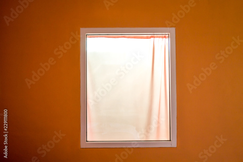 The White Window Has White Curtains Next To The Orange Walls The