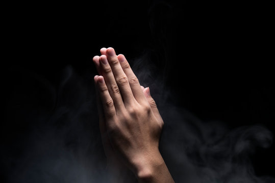 Hands with praying gesture over dark background