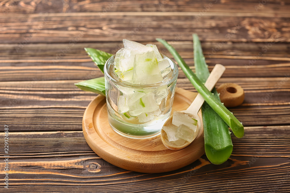 Glass and spoon with aloe vera on wooden table