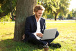 © Pixel-Shot - Handsome young businessman with laptop resting near tree in park