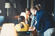© Alex from the Rock - Startup and millenial business concept. Team of four people works together in big office. Woman explains new plan changing