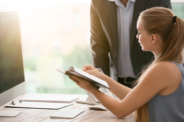 Beautiful female secretary working with colleague in office