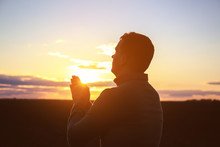 Religious Man Praying Outdoors At Sunset