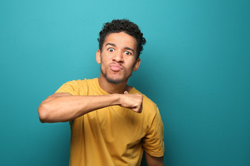 Wall Mural - Portrait of aggressive African-American man on color background