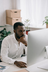 pensive handsome african american businessman working at computer in office