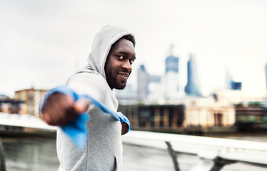 Wall Mural - Young black sportsman exercising with elastic rubber bands in London.