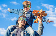 © alonaphoto - Father and son in jeans clothes and goggles pilots simulate airplane flight against the blue sky background
