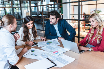 Wall Mural - business team discussing new business project at workplace with papers and laptop in office