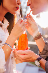 Sharing everything. Close up of a bottle with orange juice being shared by positive young couple