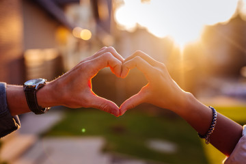 Our love. Hands of nice young people being held together while showing the heart