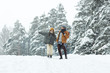 © pressmaster - Happy optimistic young couple of hikers walking over forest together and enjoying snowy day