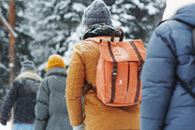 Group Of Hikers With Backpacks Walking In Line Under Snow, Tourists Hiking Together In Winter Forest